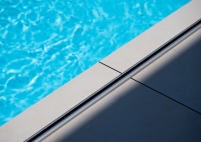 Détail du rail de la Coverseal au bord de la piscine, parfaitement intégré dans le carrelage clair de la terrasse.