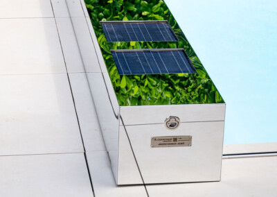 Plan rapproché du coffre miroir Coverseal, sur lequel sont intégrés deux panneaux solaires, reflétant la végétation alentour.